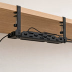 The cable tray clamped under a desk, holding a power strip and routed cables