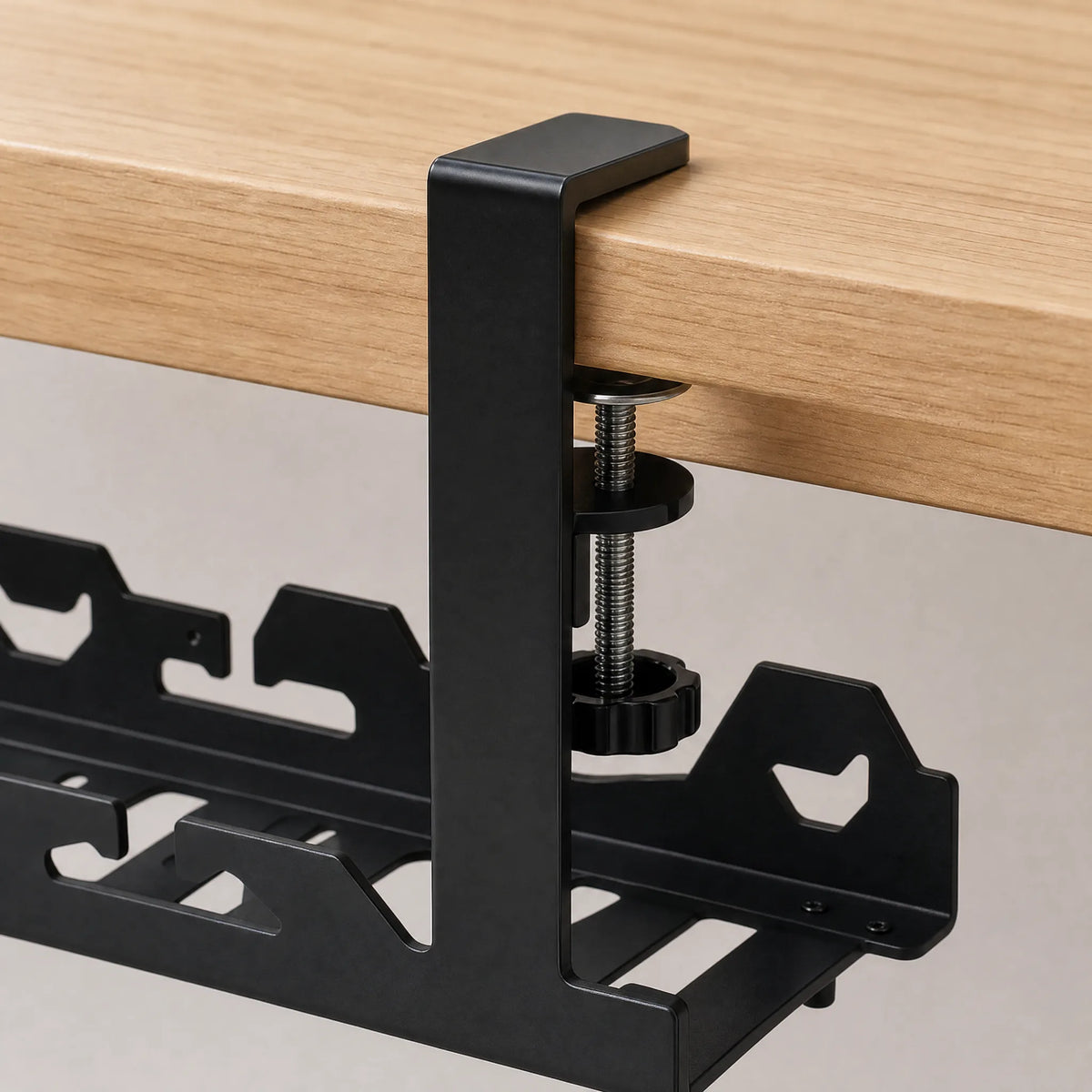 Close-up of the bracket arm hooked over the desk edge with the thumbscrew tightened